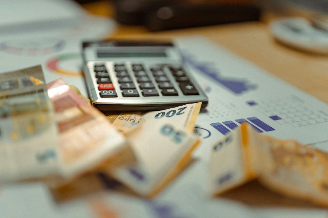 Calculadora sobre documentos financieros y billetes, imagen relacionada con la educación financiera, el presupuesto y la administración del dinero.
