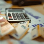 Calculadora sobre documentos financieros y billetes, imagen relacionada con la educación financiera, el presupuesto y la administración del dinero.