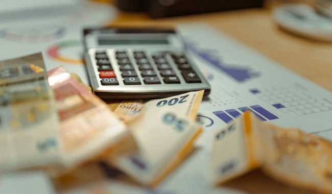 Calculadora sobre documentos financieros y billetes, imagen relacionada con la educación financiera, el presupuesto y la administración del dinero.