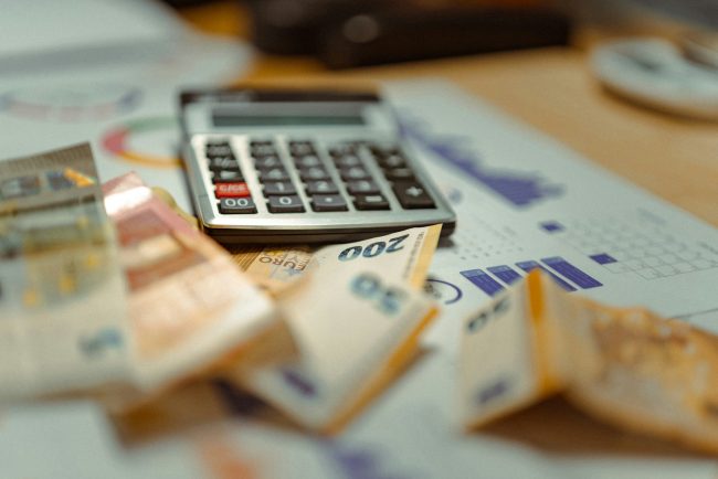 Calculadora sobre documentos financieros y billetes, imagen relacionada con la educación financiera, el presupuesto y la administración del dinero.